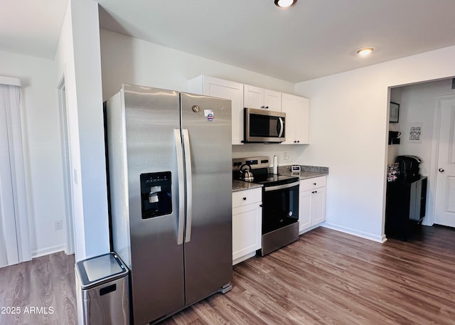 kitchen with stainless steel appliances, wood finished floors, and white cabinetry