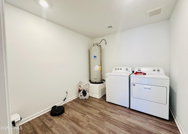 laundry room featuring electric water heater, washer and dryer, wood finished floors, and baseboards