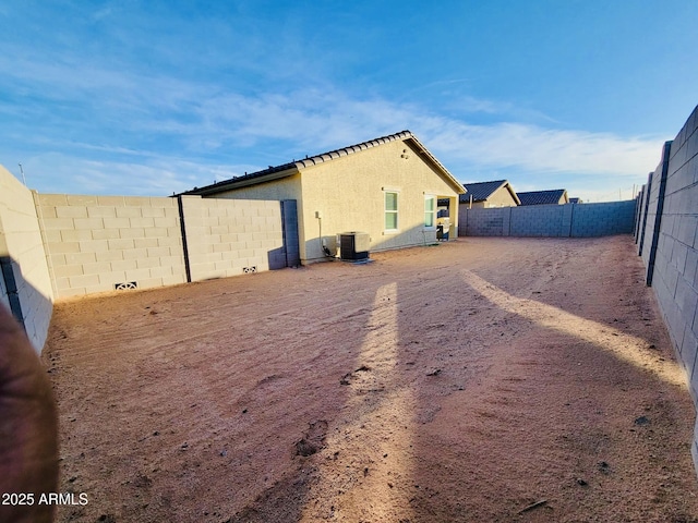 view of side of property featuring central AC unit, stucco siding, and a fenced backyard