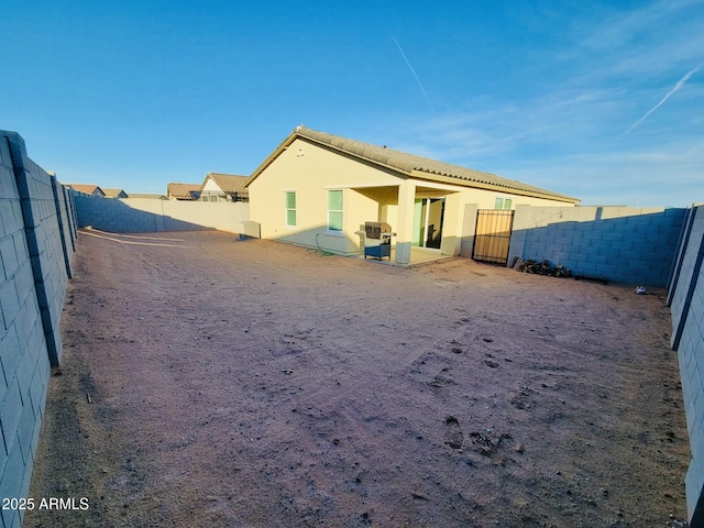 back of property featuring a fenced backyard, a tile roof, and stucco siding
