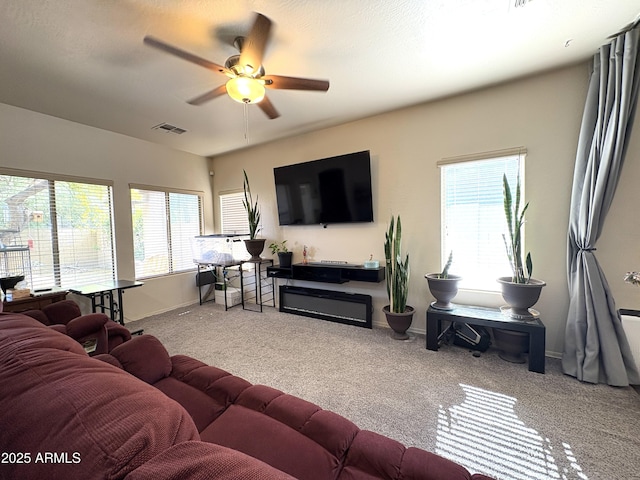 living room featuring carpet floors, ceiling fan, visible vents, and a healthy amount of sunlight