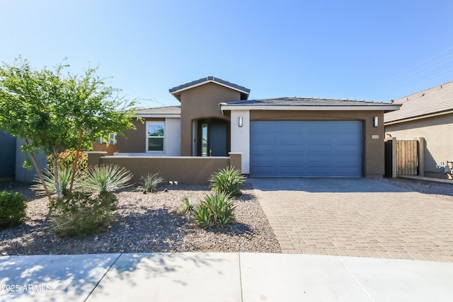 view of front facade with stucco siding, decorative driveway, a garage, and fence