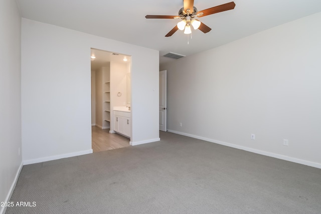 unfurnished bedroom featuring a ceiling fan, visible vents, baseboards, light colored carpet, and connected bathroom