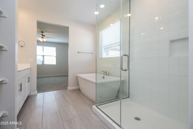 bathroom featuring vanity, baseboards, a freestanding tub, a stall shower, and ceiling fan