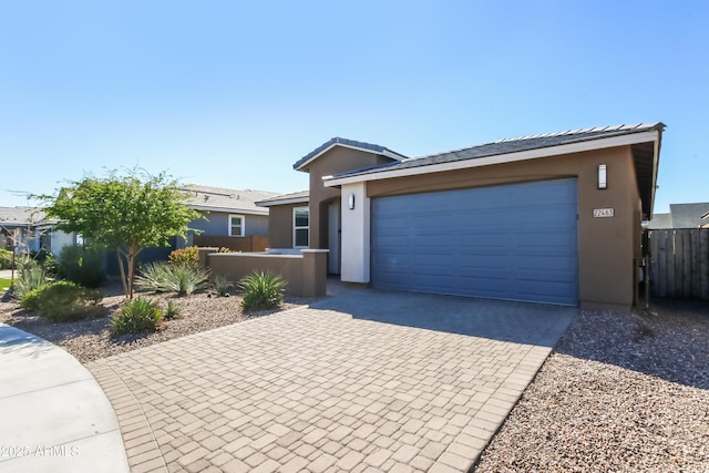 ranch-style house featuring stucco siding, decorative driveway, a garage, and fence