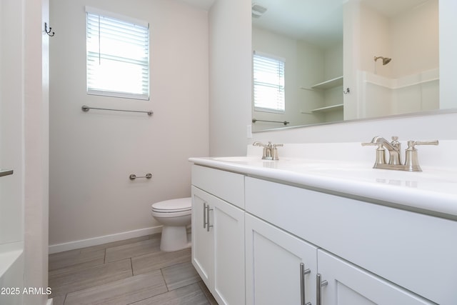 full bathroom featuring baseboards, toilet, walk in shower, and a sink