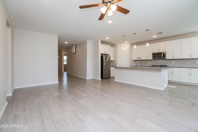 kitchen with visible vents, tasteful backsplash, open floor plan, stainless steel appliances, and ceiling fan