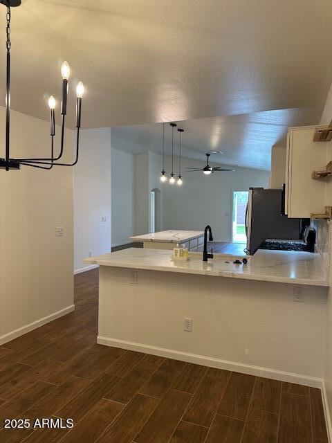 kitchen with dark wood-style flooring, ceiling fan, light countertops, freestanding refrigerator, and a peninsula