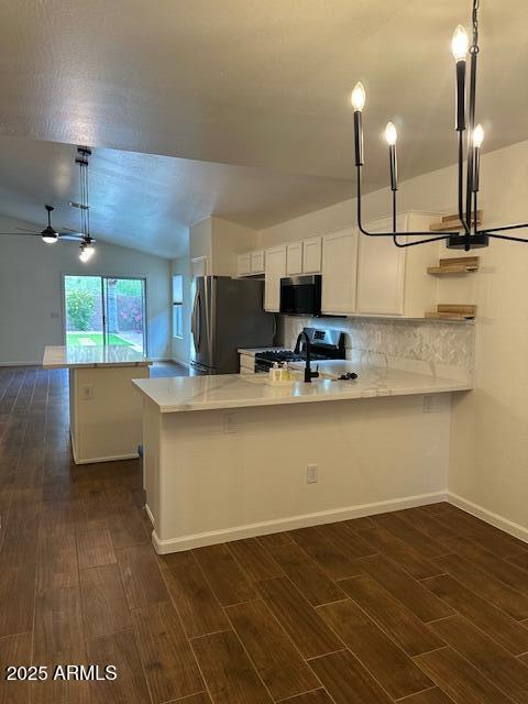 kitchen featuring light countertops, dark wood finished floors, stainless steel appliances, a peninsula, and lofted ceiling