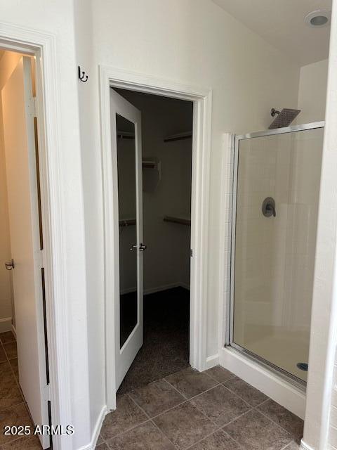 full bath with tile patterned floors, baseboards, a shower stall, and a spacious closet