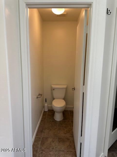 bathroom with baseboards, toilet, and visible vents