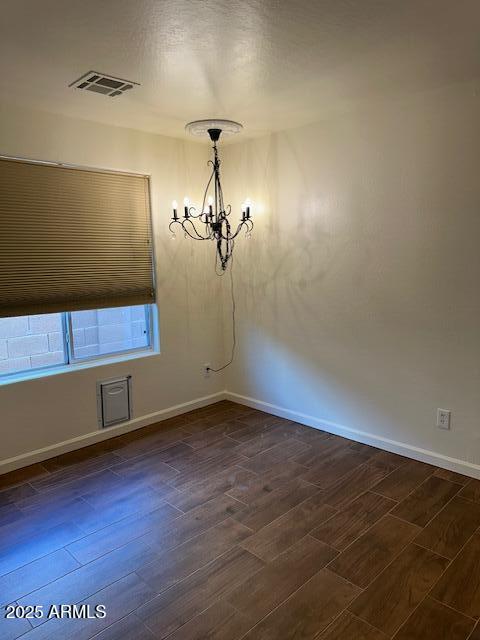 unfurnished dining area featuring a chandelier, baseboards, visible vents, and dark wood-type flooring
