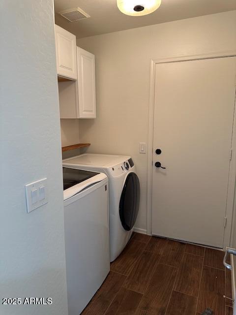 clothes washing area featuring independent washer and dryer, wood finish floors, visible vents, and cabinet space