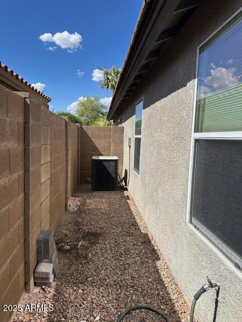 view of property exterior with central air condition unit, stucco siding, and a fenced backyard
