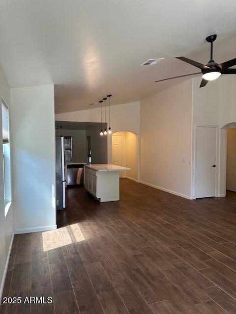 unfurnished living room with arched walkways, a ceiling fan, visible vents, and dark wood-type flooring