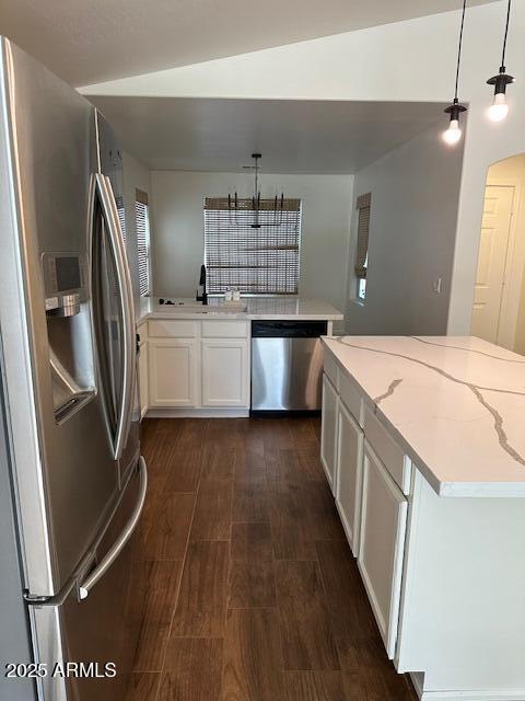 kitchen with white cabinets, light stone countertops, stainless steel appliances, and decorative light fixtures