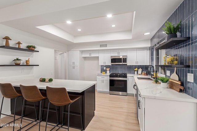 kitchen featuring appliances with stainless steel finishes, white cabinetry, a kitchen breakfast bar, and sink