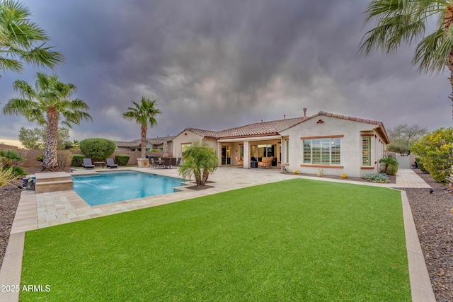 view of swimming pool with pool water feature, a patio area, and a lawn