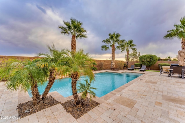 pool at dusk with a patio area