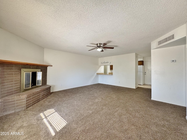 unfurnished living room with carpet flooring, ceiling fan, a textured ceiling, and a brick fireplace