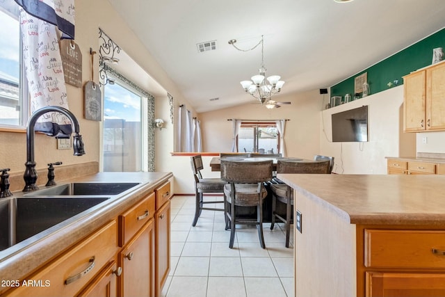 kitchen featuring pendant lighting, sink, light tile patterned floors, lofted ceiling, and a chandelier