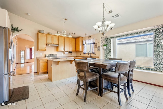 dining area featuring light tile patterned flooring, lofted ceiling, a chandelier, and sink