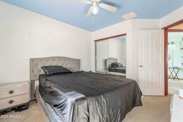 bedroom with ceiling fan, light colored carpet, and a closet