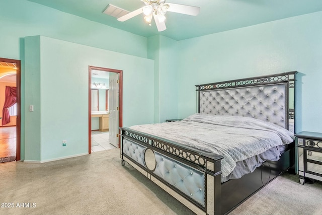 bedroom featuring ceiling fan, ensuite bath, and light carpet