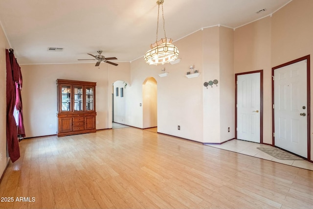 empty room featuring crown molding, light hardwood / wood-style flooring, high vaulted ceiling, and ceiling fan