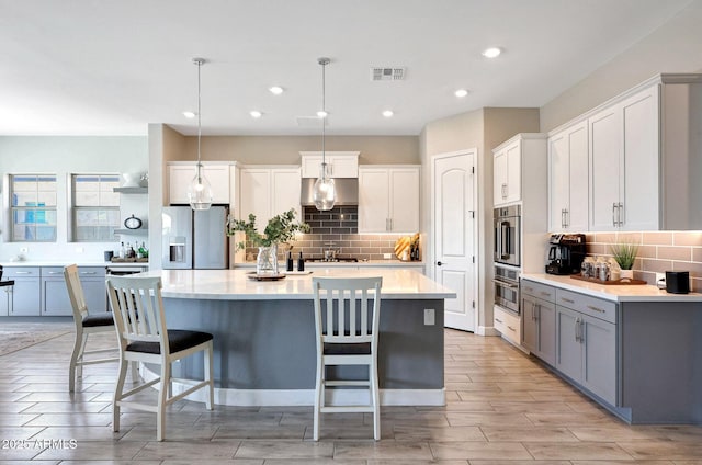 kitchen with backsplash, a breakfast bar area, stainless steel fridge with ice dispenser, and light countertops