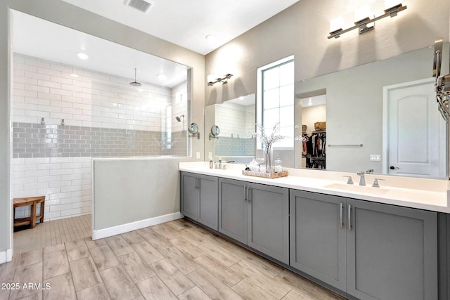 bathroom featuring visible vents, a sink, walk in shower, and tile walls