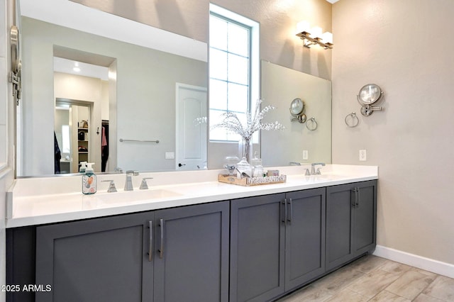 full bathroom with double vanity, baseboards, and a sink