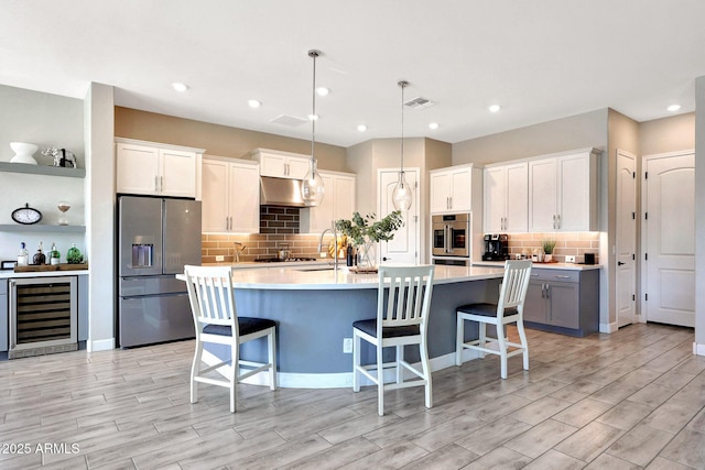 kitchen with visible vents, tasteful backsplash, under cabinet range hood, wine cooler, and stainless steel appliances