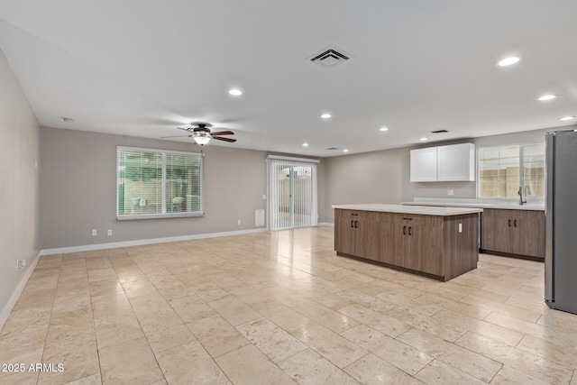 kitchen with freestanding refrigerator, a kitchen island, recessed lighting, light countertops, and a ceiling fan