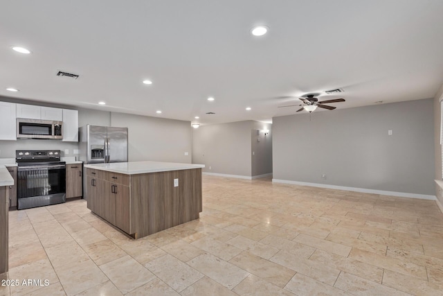 kitchen with stainless steel appliances, a kitchen island, recessed lighting, light countertops, and ceiling fan