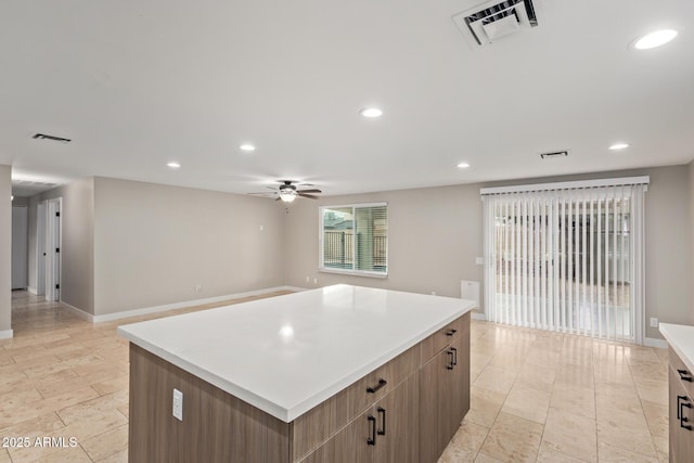 kitchen with ceiling fan, a kitchen island, light countertops, recessed lighting, and baseboards
