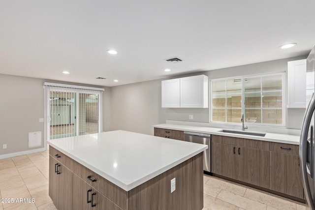 kitchen with a sink, dishwasher, light countertops, a center island, and recessed lighting