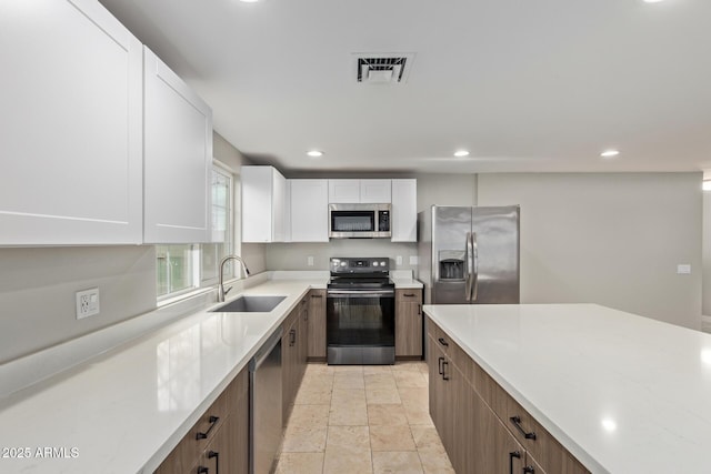 kitchen featuring stainless steel appliances, a sink, light countertops, recessed lighting, and white cabinets