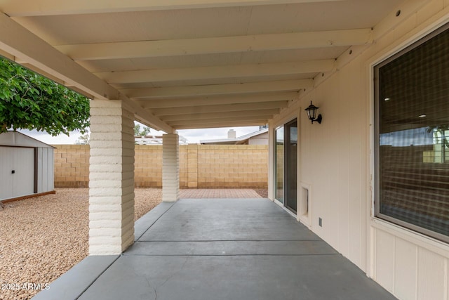 view of patio featuring a storage shed, fence, and an outdoor structure