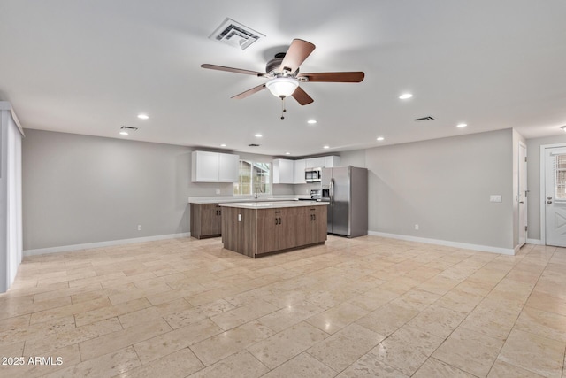 kitchen featuring stainless steel refrigerator with ice dispenser, a kitchen island, light countertops, ceiling fan, and recessed lighting