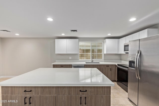 kitchen featuring appliances with stainless steel finishes, a sink, a center island, white cabinets, and recessed lighting