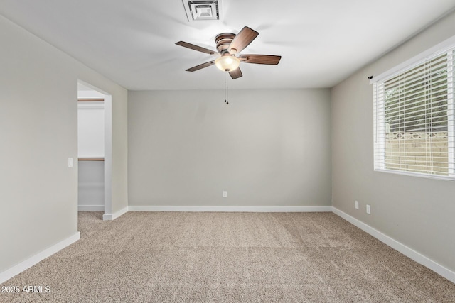 carpeted spare room featuring a ceiling fan and baseboards