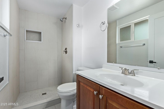 bathroom featuring toilet, tiled shower, and vanity