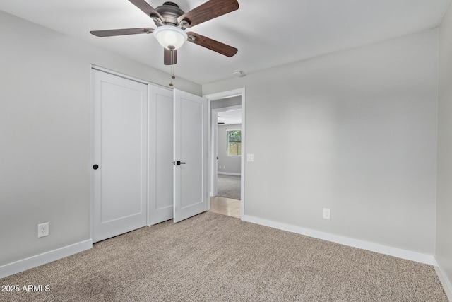 unfurnished bedroom featuring carpet floors, baseboards, a closet, and a ceiling fan