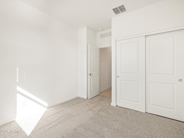 unfurnished bedroom with light carpet, a closet, visible vents, and baseboards