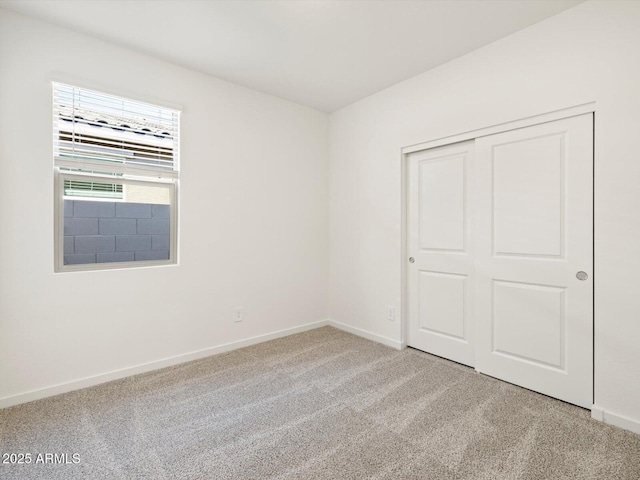 unfurnished bedroom with light carpet, a closet, and baseboards