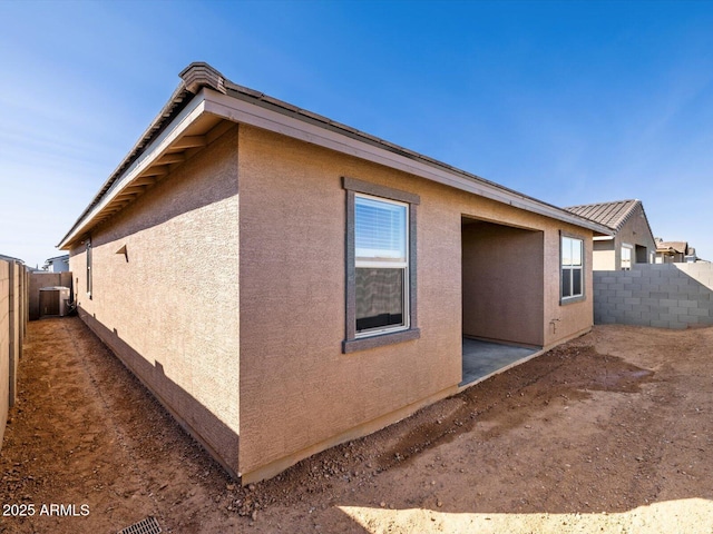 view of side of property with a fenced backyard and stucco siding