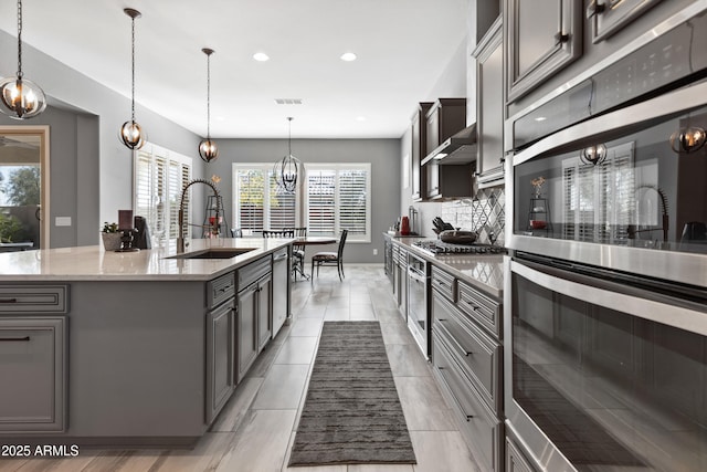 kitchen featuring stainless steel appliances, a sink, visible vents, gray cabinets, and light stone countertops