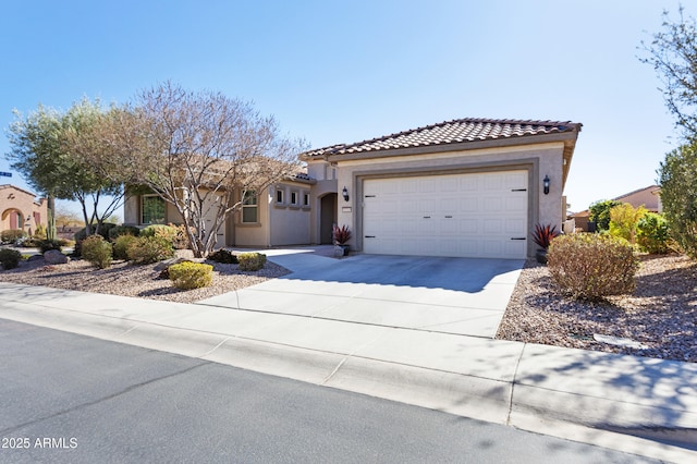 view of front of property with concrete driveway, a tiled roof, an attached garage, and stucco siding