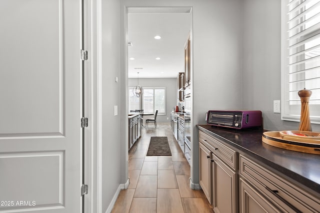 hall featuring baseboards, recessed lighting, light tile patterned flooring, and a toaster